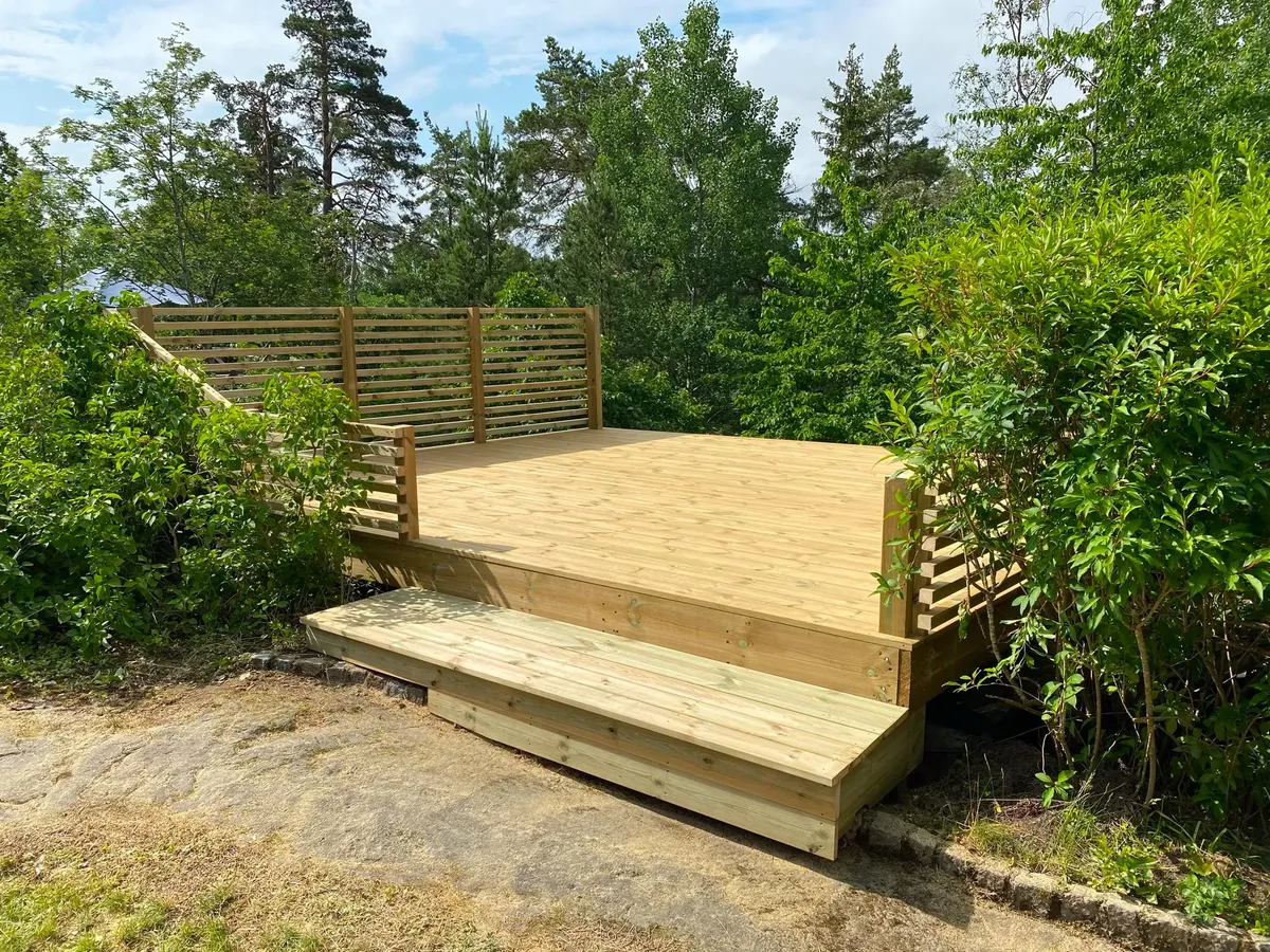 Trädäck med trappa och spaljé i skogsmiljö
