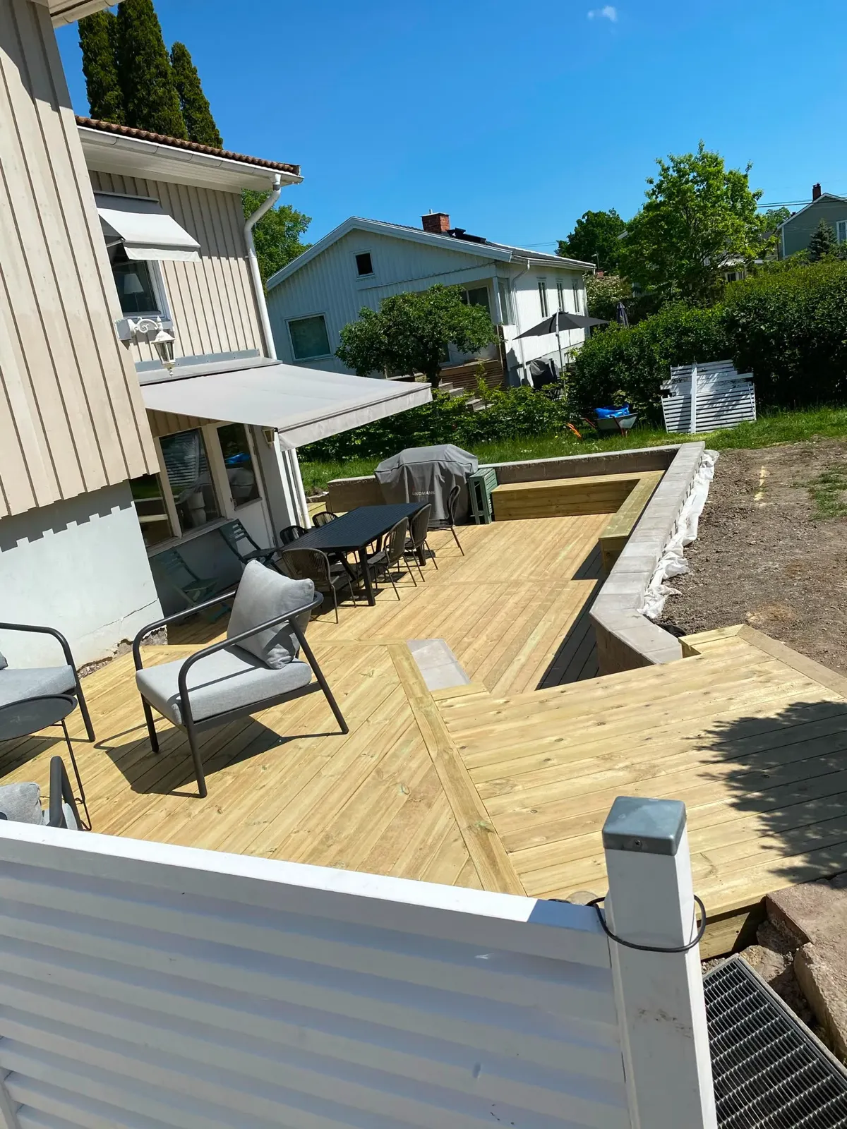 Trädäck med möbler vid vitt hus