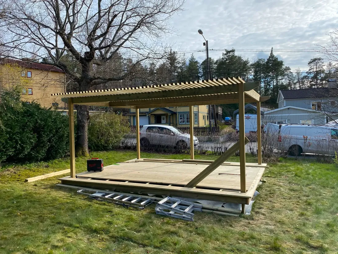 Nybyggd pergola i trä på gräsmatta