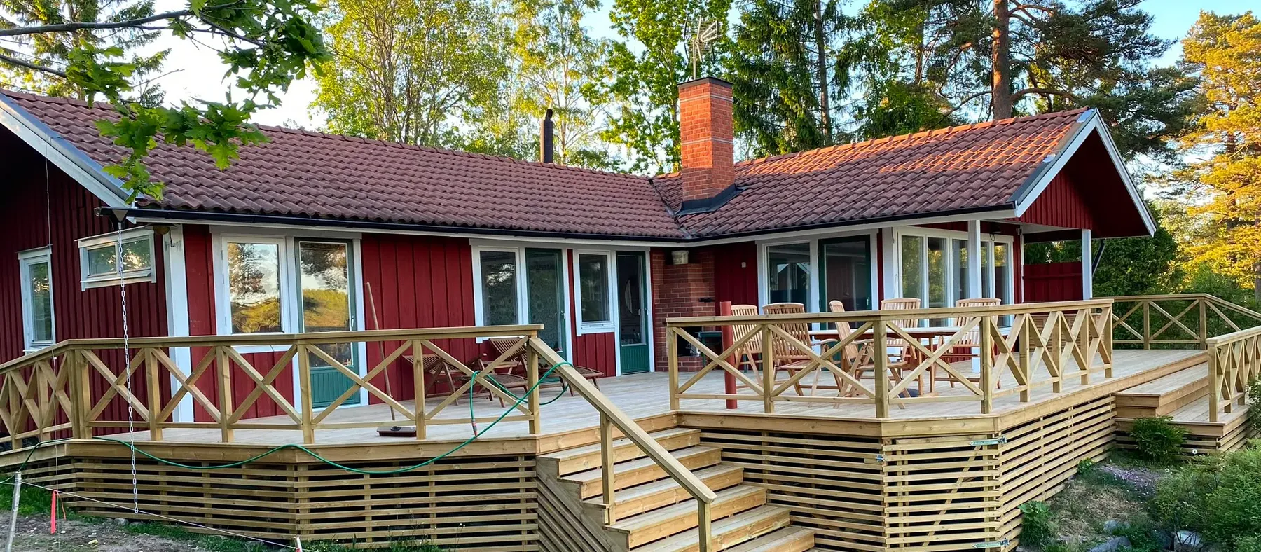 Rödmålad villa med ny altan i kvällssol