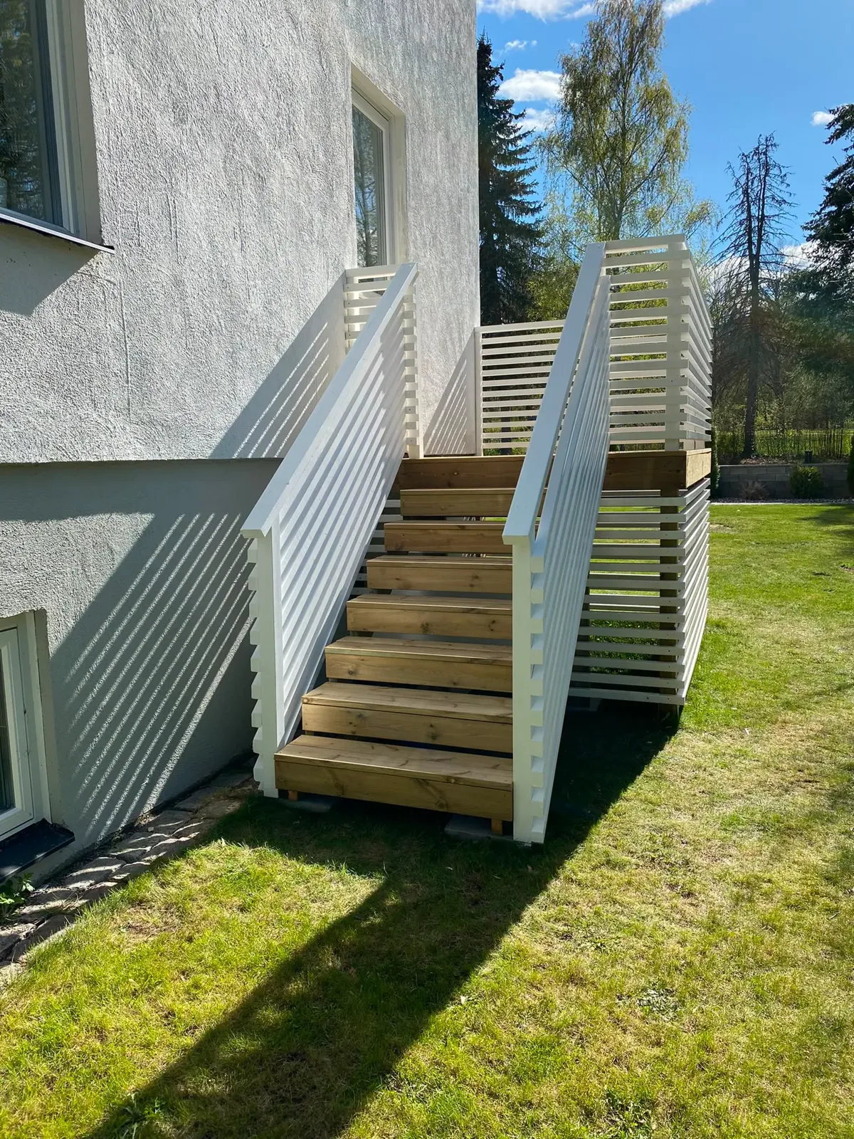 Vitmålad utomhustrappa med räcke